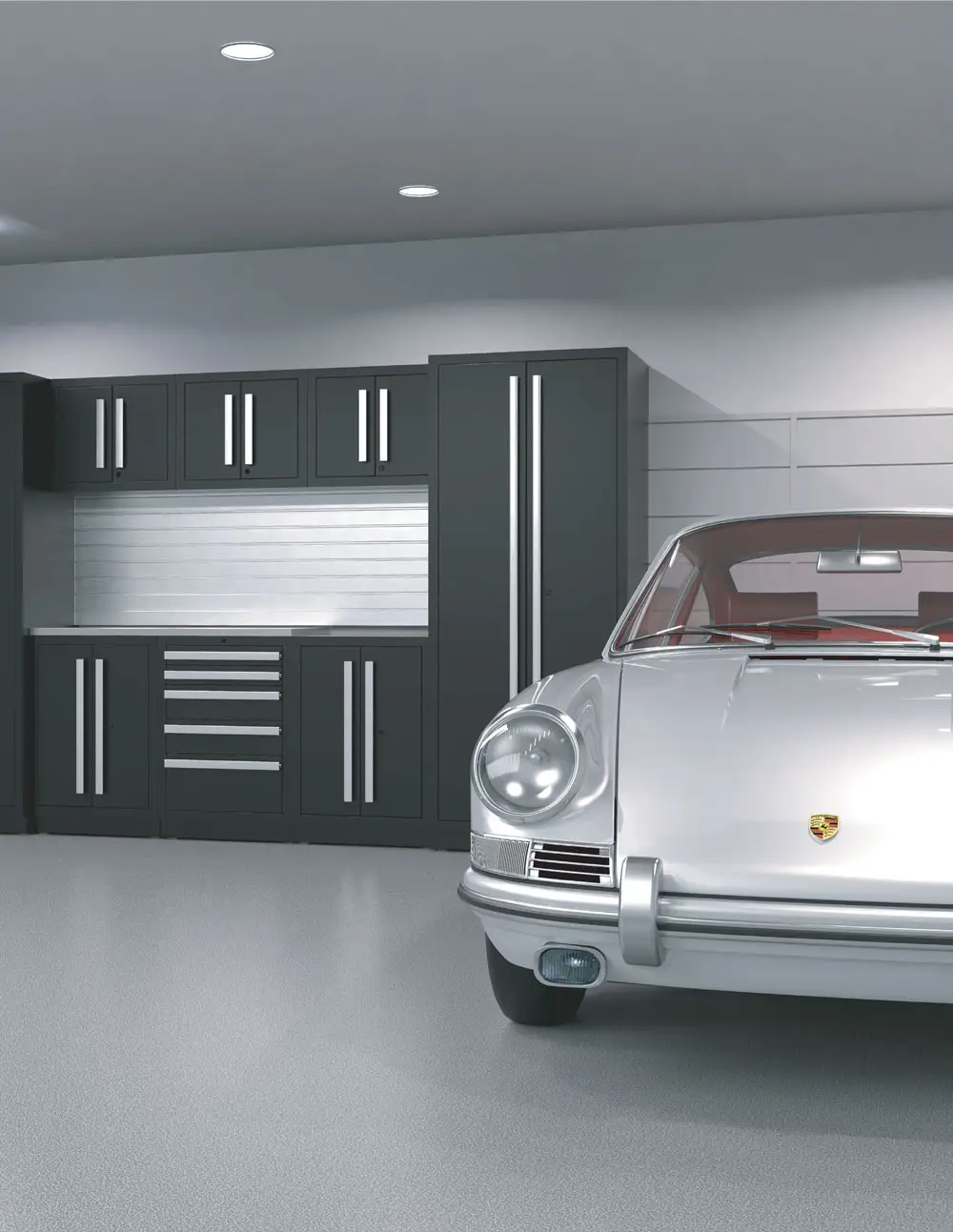 A sleek, classic silver sports car is parked in a modern, tidy garage featuring black cabinets with silver handles, drawers, and a metallic backsplash. The environment is well-lit with recessed ceiling lights, highlighting the organized cabinets and polished space.