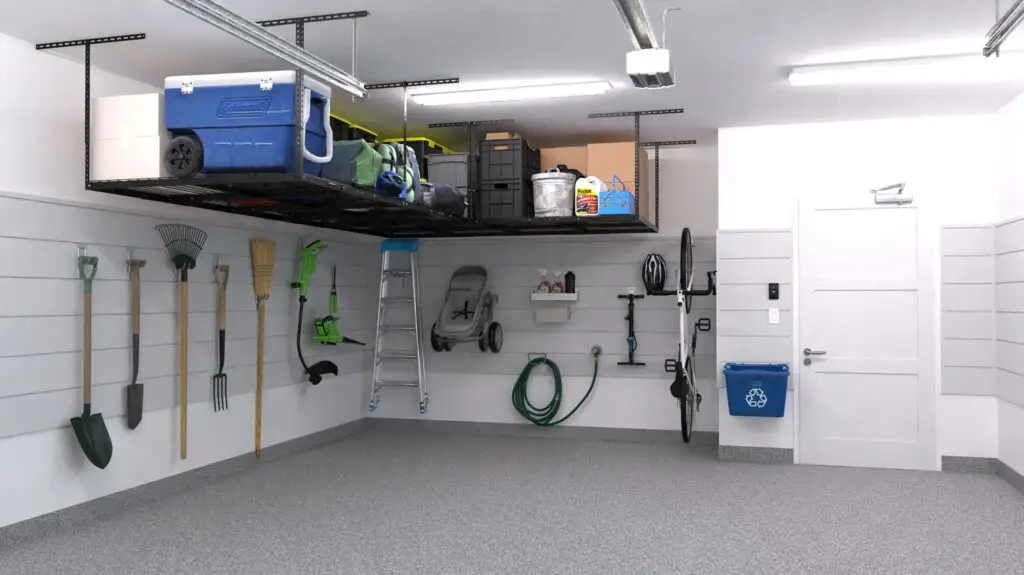 A tidy garage, reminiscent of a Garage Kings Poto Gallery, features a variety of tools hanging neatly on the left wall, including a broom, rake, and shovel. Overhead, a storage rack holds a cooler and various boxes. On the right wall, there's a bike, a coiled hose, a step ladder, and a blue recycling bin.