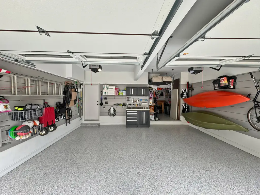 A tidy garage franchise with wall-mounted storage holding a bike, kayaks, and various tools.