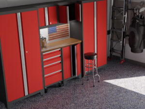 A garage workspace with red cabinets, a wooden workbench, a black and red stool, an American flag wall decoration, and a golf bag in the corner on a speckled blue and gray floor—an ideal template for your May workspace makeover.