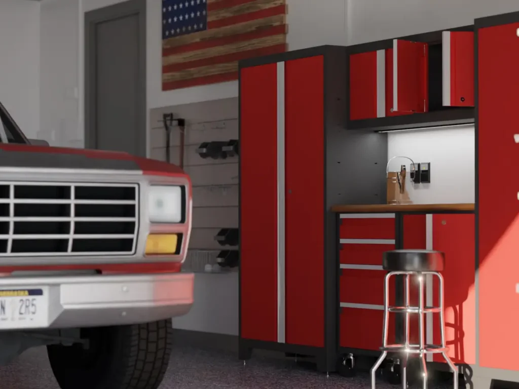 A red and white truck is parked in a garage makeover space with red tool cabinets, a workbench, a black stool, and an American flag hanging on the wall—a perfect Memorial Day backdrop.
