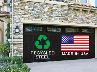 amarr-sustainble-USAr A garage with stone façade features two large black doors each displaying different logos. The left door shows a green recycling symbol with the text "RECYCLED STEEL" underneath, and the right door displays the American flag with the text "MADE IN USA.